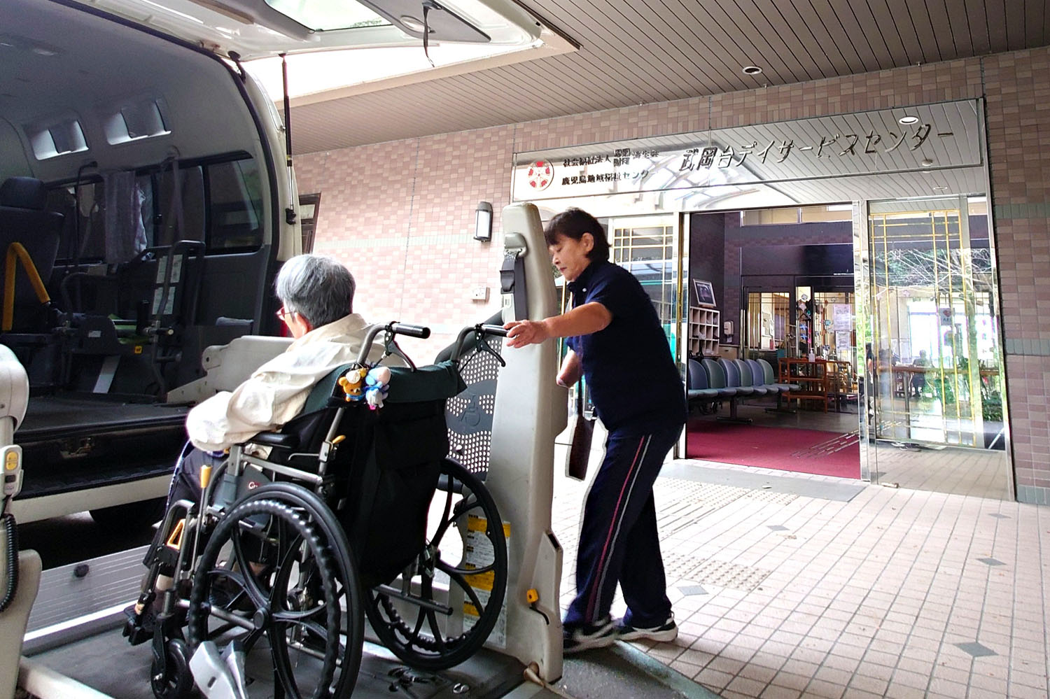 介護スタッフが車いす利用者の送迎をサポートしている玄関・車寄せ